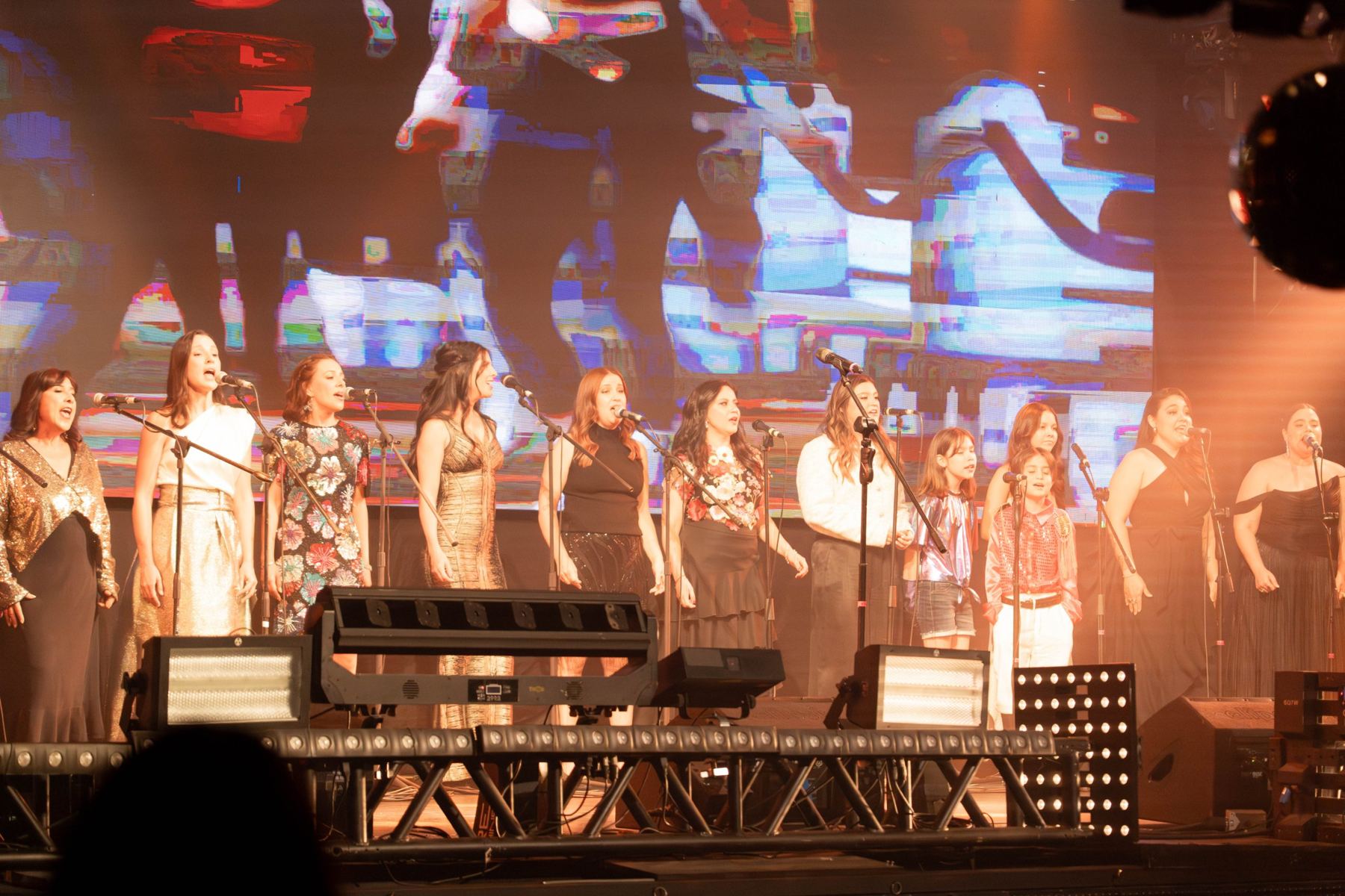 Alumnos de todas las edades cantando juntos en el escenario del concierto anual