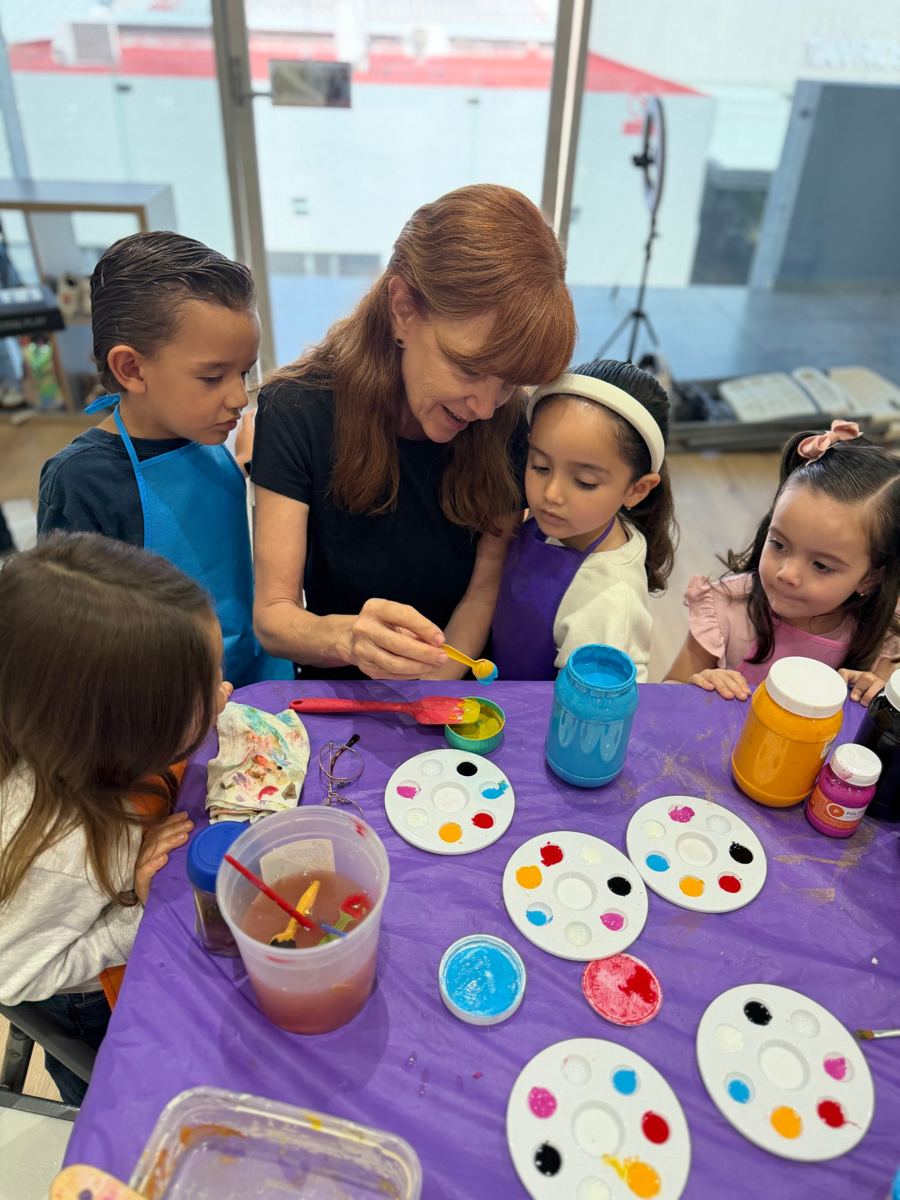 Maestra de pintura mezclando colores con niños pequeños